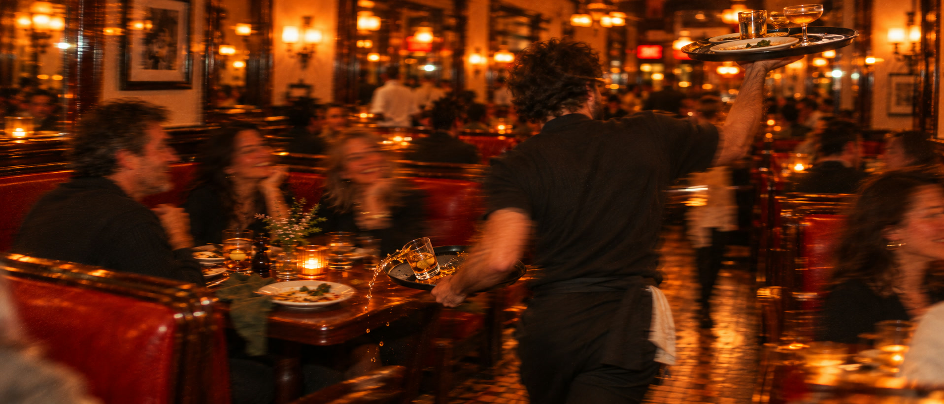 Ein Kellner trägt Getränke durch ein volles Restaurant